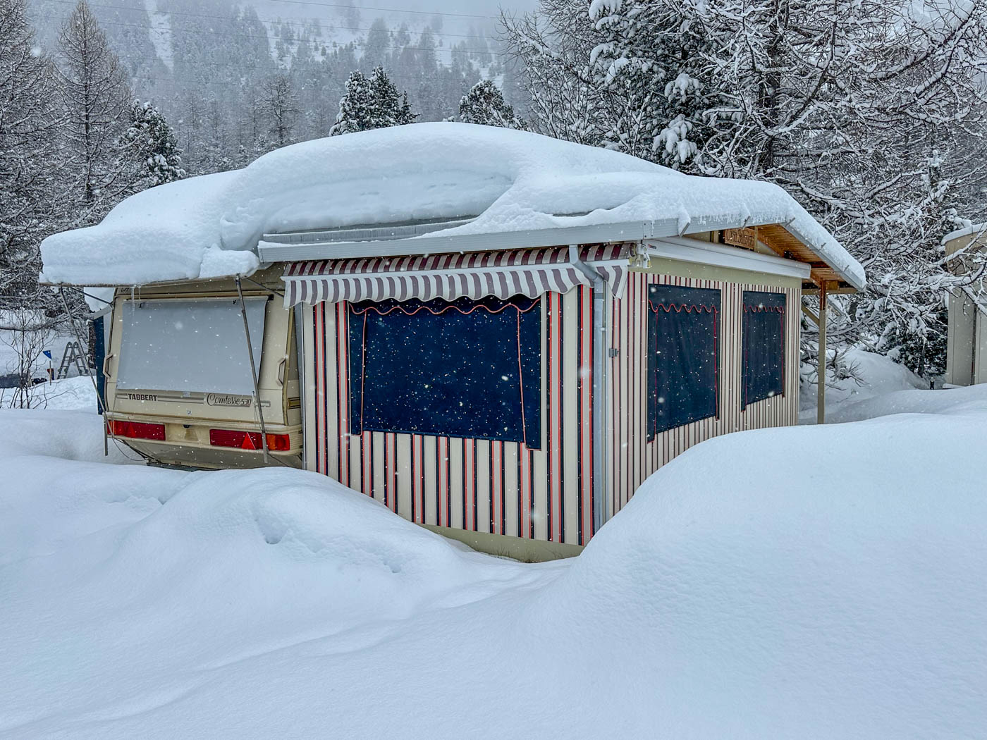 Eingeschneiter Wohnwagen mit Vorzelt beim Wintercamping